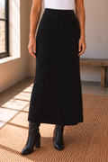 The Haven Black Ribbed Knit Midi Skirt styled with a white top and black knee high boots