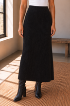 The Haven Black Ribbed Knit Midi Skirt styled with a white top and black knee high boots